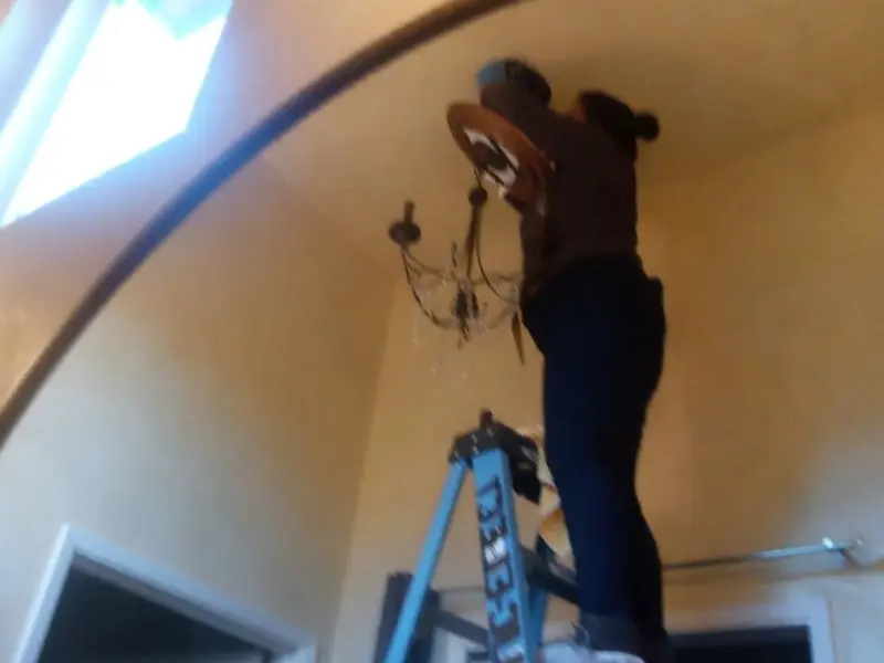 Electrician installing a chandelier in a Tipton residence